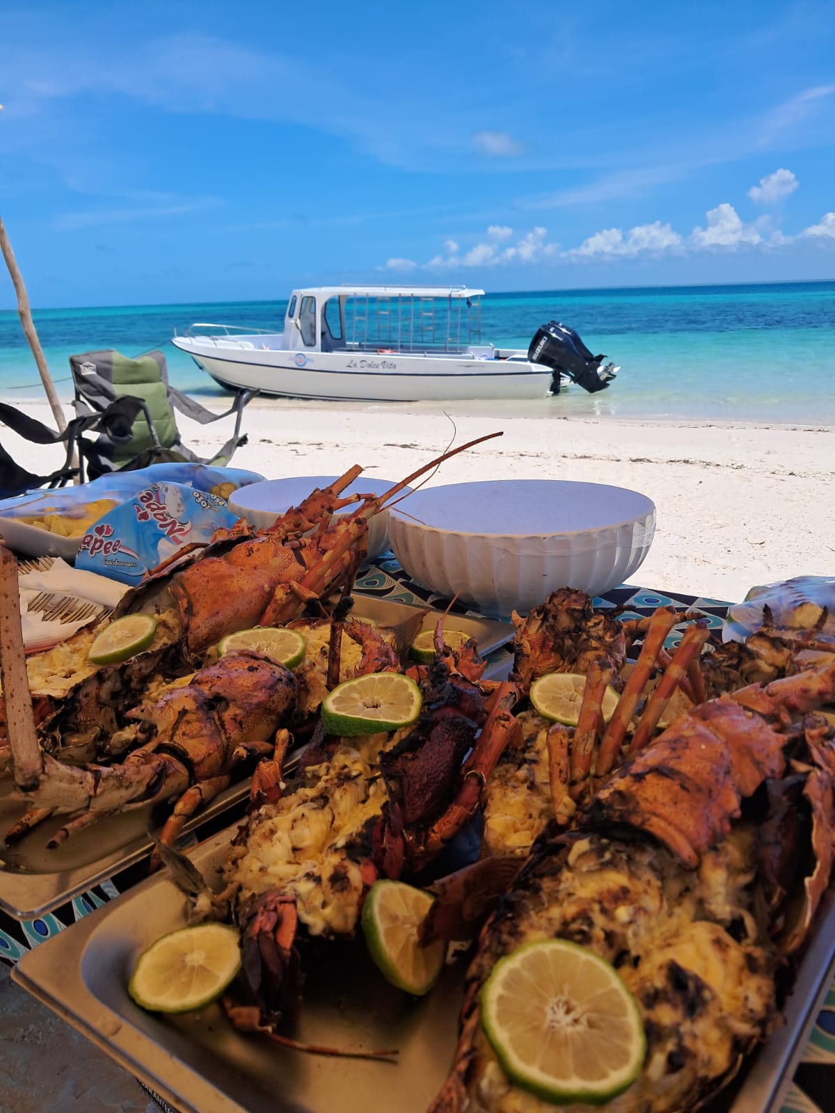 Grilled lobster lunch on the beach with La Dolce Vita boat behind