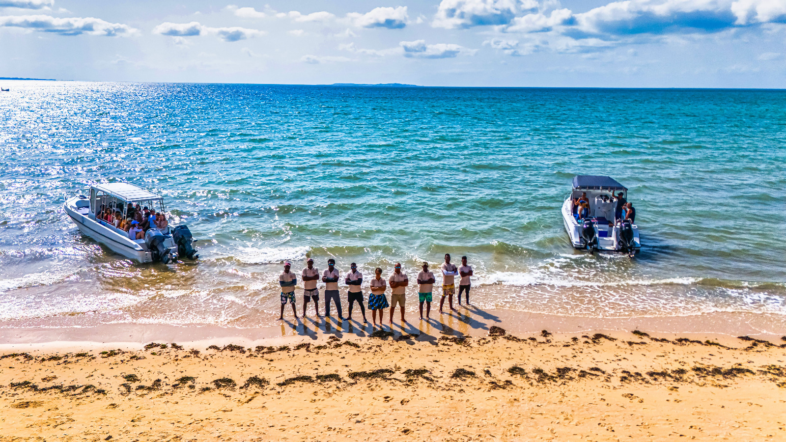 The team on the beach with two boats
